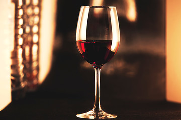 Crystal clear wine glass with traditional round goblet shape filled with dark red wine. Vintage photo