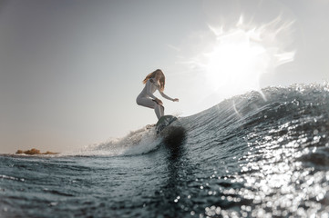 Blonde girl riding on the wakeboard on the bending knees