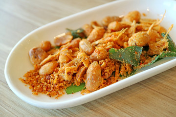 Hot and Spicy Thai Style Roasted Peanuts with Herb Served on Wooden Table 