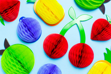 Flat lay bright tropical fruits of paper, strawberry, cherries, pineapple, apple, plum on blue background top view copy space. Minimalistic creative summer food concept, origami paper fruit