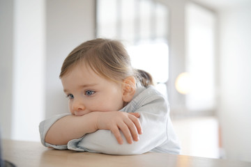 Portrait of adorable girl indoors with arms crossed on table
