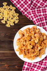 Pasta with chicken, spices and tomato sauce on dark wooden background. 