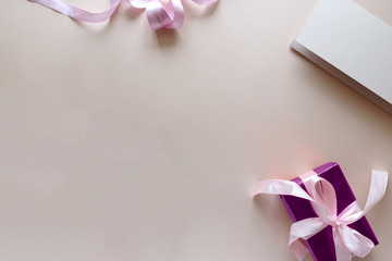 Bouquet of white and purple tulips, gift box and blank paper on pink background. Top view. Flat...