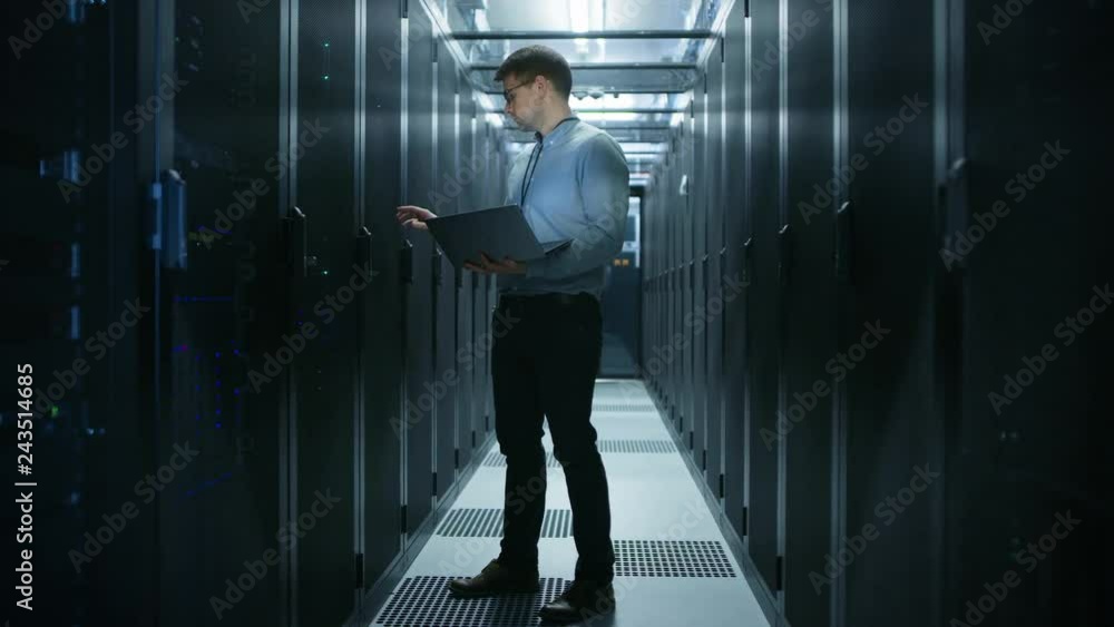 Leinwandbilder In Data Center IT Engineer Stands Before Working Server Rack Doing Routine Maintenance Check and Diagnostics Using Laptop. Concept of Cloud Computing, Artificial Intelligence, Supercomputer