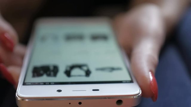 Woman looks at the goods in the online shoes store. People using Smartphone, online shopping. Close up. 4K UHD. Screen is blurred.