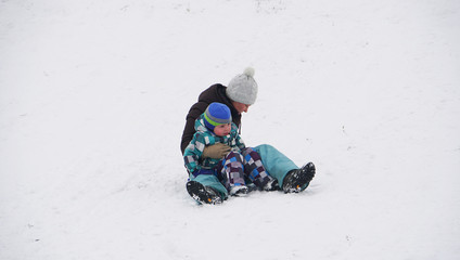 Fototapeta na wymiar Mother sitting with her baby on the snow in winter park.