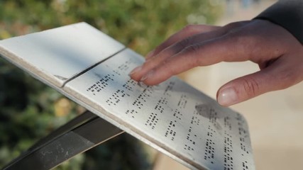 Blind girl or man reads text written in Braille font sunny day street board. People on vacation, tourist description for people with disabilities