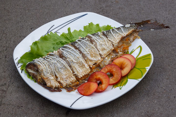 Baked mackerel with green lettuce and fruit. Close-up
