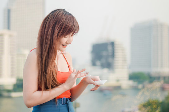 Young woman applying sunscreen lotion standing outdoors at the urban location during the sunny weather
