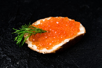 Red caviar with bread on black
