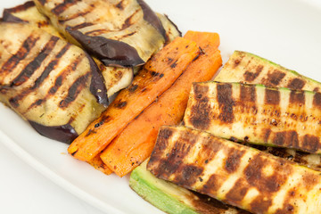 Delicious grilled vegetables on white plate. Carrots, eggplant and zucchini