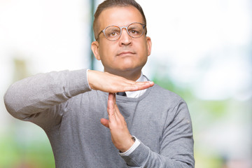 Middle age bussines arab man wearing glasses over isolated background Doing time out gesture with...