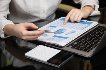 Female hands work with chart on a background of notebook