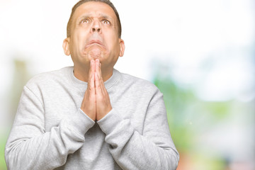 Middle age arab man wearing sport sweatshirt over isolated background begging and praying with hands together with hope expression on face very emotional and worried. Asking for forgiveness