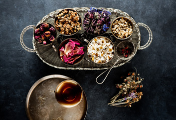 Medicinal dried herbs in cups and herbal tea. Herbal medicine concept, top view.