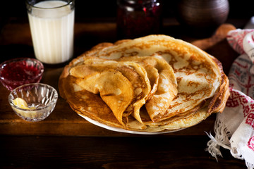 Russian pancakes crepes with butter and raspberry jam on rustic wooden background