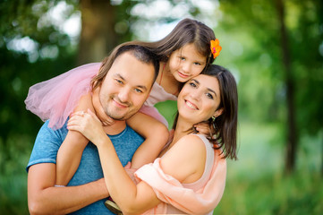 happy family is relaxing in nature, hugging and smiling together