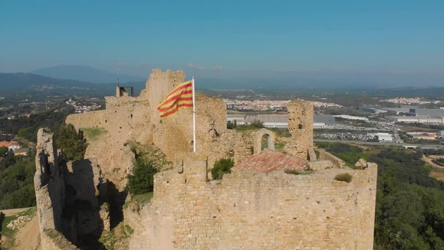 Beautiful detail of the Catalonia flag fluttering on Palafolls Castle ruins on a sunny day. Catalonia Spain. Aerial view travelling