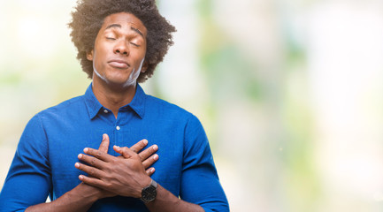 Naklejka na ściany i meble Afro american man over isolated background smiling with hands on chest with closed eyes and grateful gesture on face. Health concept.