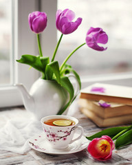 on the windowsill a cup of tea, books, flowers