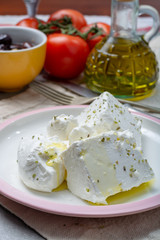 Fresh young soft white Feta cheese with olive oil on plate seasoned with dried oregano herb