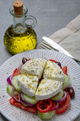 Traditional greek salad made with fresh cucumber, tomato, paprika, red onion, kalamata olives, white salted feta cheese with oregano served with olive oil