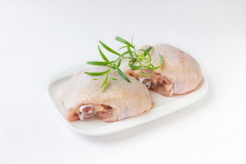 Raw chicken thighs with rosemary  on cutting board, on a white background.