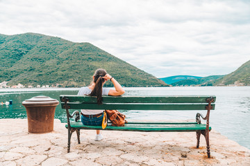 woman sitting at bench with beautiful view of sea and mountains