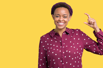 Beautiful young african american woman wearing head scarf over isolated background smiling and confident gesturing with hand doing size sign with fingers while looking and the camera. Measure concept.