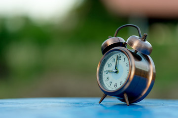 Golden alarm clock picture placed on a blue table, green background Punctual concept With copy space