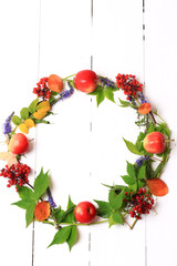 autumn wreath with flowers and berries on a white wooden background