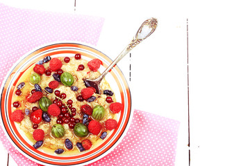 breakfast oatmeal with berries and honey on white wooden background flat style top view overhead...