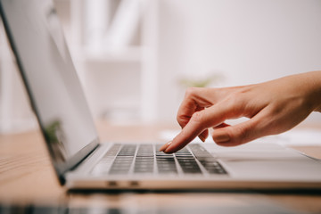 partial view of businesswoman typing on laptop at workspace