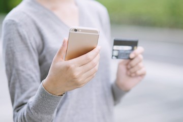 close up young female hands holding credit card and using mobile smart phone. Online shopping purchase Sell or Payment. Technology Pay online finance concept.