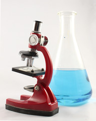 Microscope and erlenmeyer flask with blue liquid isolated on white background