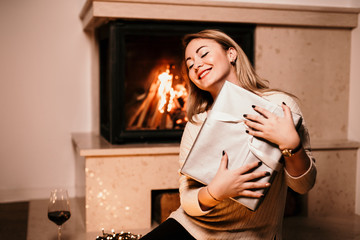Girlfriend smiling and opening presents by the fireplace. Romantic gesture