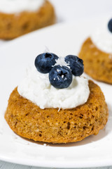 pumpkin cakes with cream and blueberries on white plate, vertical