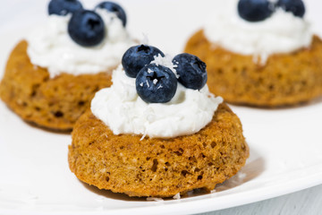 pumpkin cakes with cream and blueberries on white plate, closeup