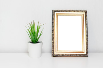 Minimalistic interior design with photo frame and a plant in white pot on a desk