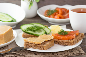 Traditional Norwegian breakfast, sandwiches with brown cheese brunost, sandwiches with cucumber and trout.