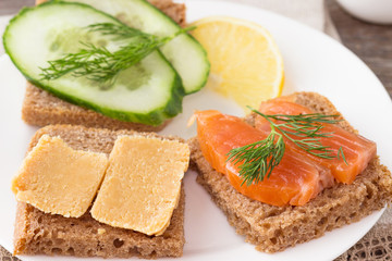 Traditional Norwegian breakfast, sandwiches with brown cheese brunost, sandwiches with cucumber and trout.