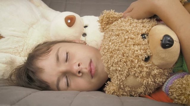 Teen girl sleeping with toys. The girl sleeps hugging a teddy bear.