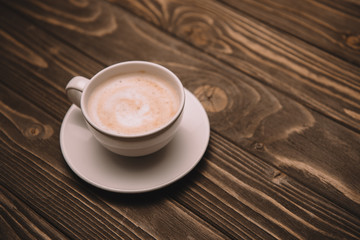 white saucer and cup with cappuccino on wooden table