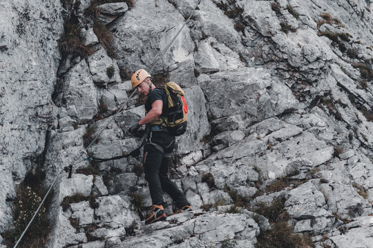 Image of young man mountaineer climbing on a rock in the mountains