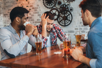 Multicultural male friends playing cards, having rest