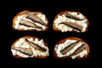 Sandwich with sprats, eggs and mayonnaise on black background.