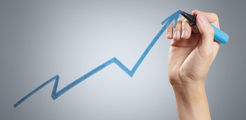 Hand drawing a growing graph using a blue marker on gray background