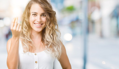 Beautiful young blonde woman over isolated background Doing Italian gesture with hand and fingers confident expression