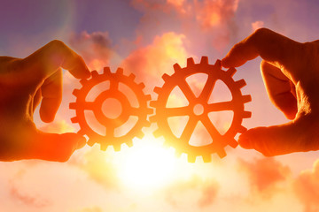 gears in the hands of people in the sky. the mechanism of the interaction of the two.