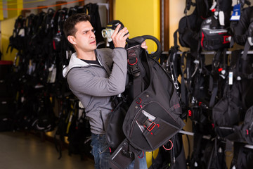 Sporty male is trying new diving vest in shop